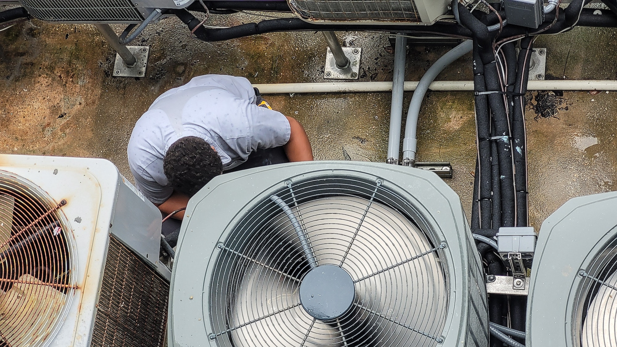HVAC technician millennial is Latino working to maintain high efficiency heating and cool at beach.